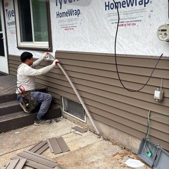 Menomonee Falls home during siding installation with worker applying high-performance Canyon vinyl siding over Tyvek wrap and insulation boards by Modern Exterior