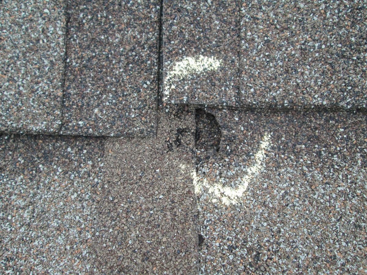 Close up of hail damage on asphalt roof shingles.