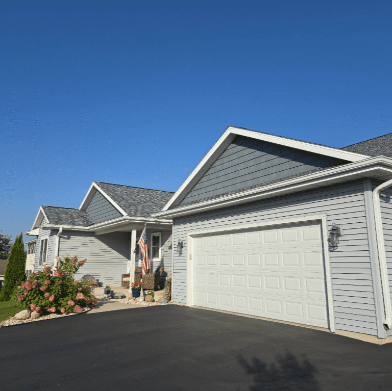Before photo of the garage exterior of an Oconomowoc, WI home showing hail-damaged siding and worn trim prior to exterior renovation by Modern Exterior.