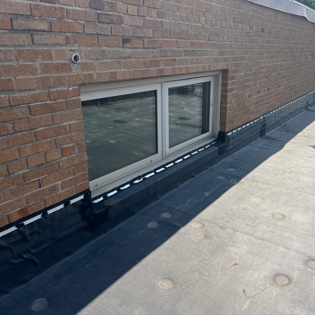 Modern Exterior EPDM roofing with wall flashing detail sealed along brick wall and window on flat roof