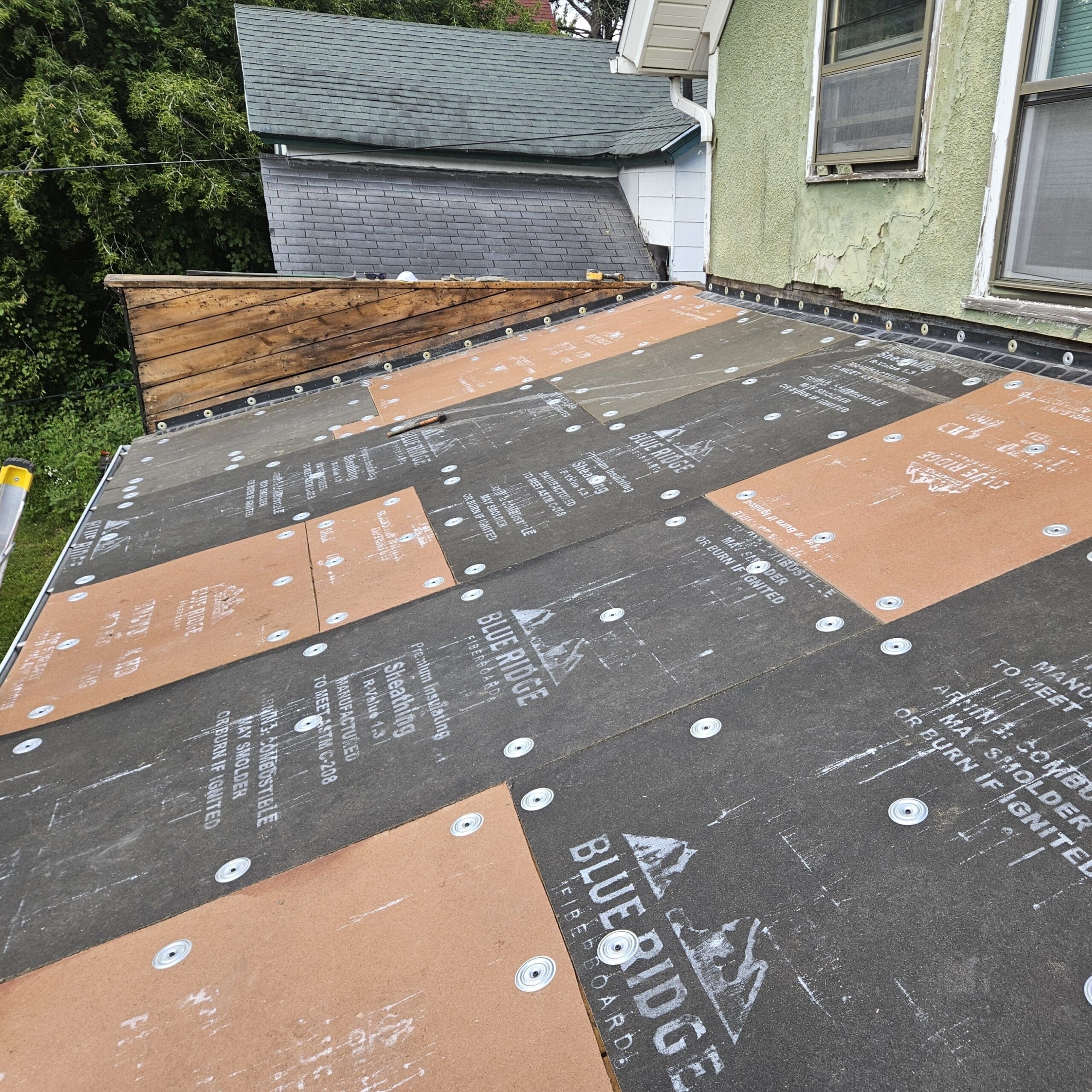Modern Exterior preparing flat roof with insulation boards and fasteners before EPDM roofing installation on residential addition