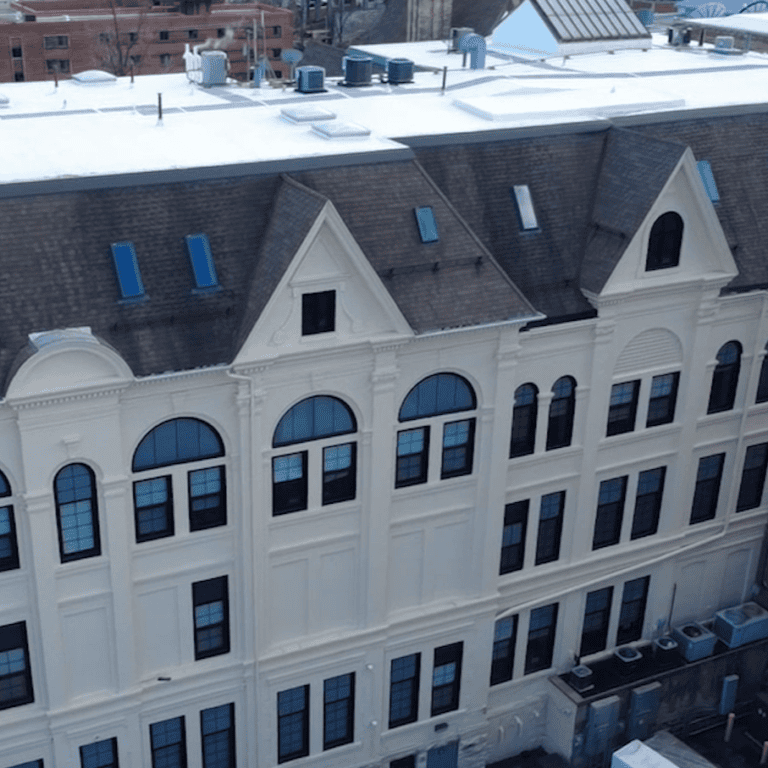 Rear aerial view of the existing commercial shingle roof and skylights before replacement on a large Milwaukee property.