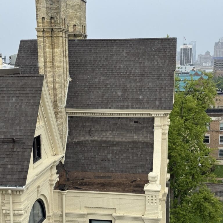 Existing asphalt shingles on a large steep-slope commercial roof in Milwaukee before complete roof replacement.